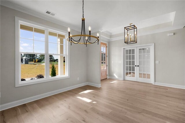 unfurnished dining area featuring a wealth of natural light, french doors, a chandelier, and light hardwood / wood-style floors