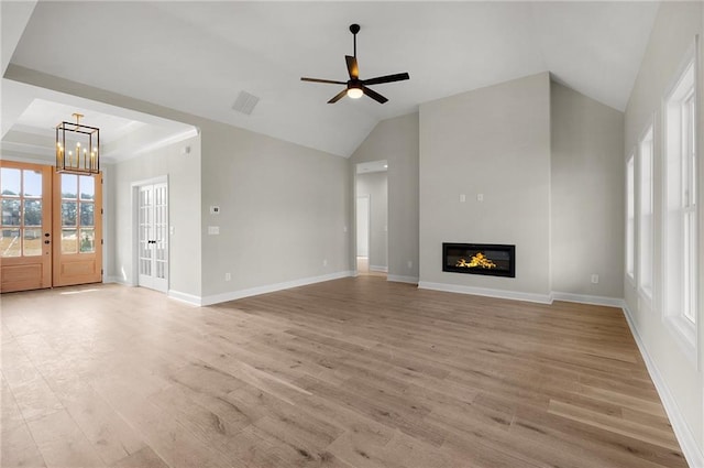 unfurnished living room with french doors, light hardwood / wood-style flooring, ceiling fan with notable chandelier, and lofted ceiling