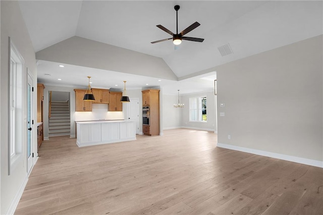 unfurnished living room featuring ceiling fan with notable chandelier, light hardwood / wood-style floors, and vaulted ceiling