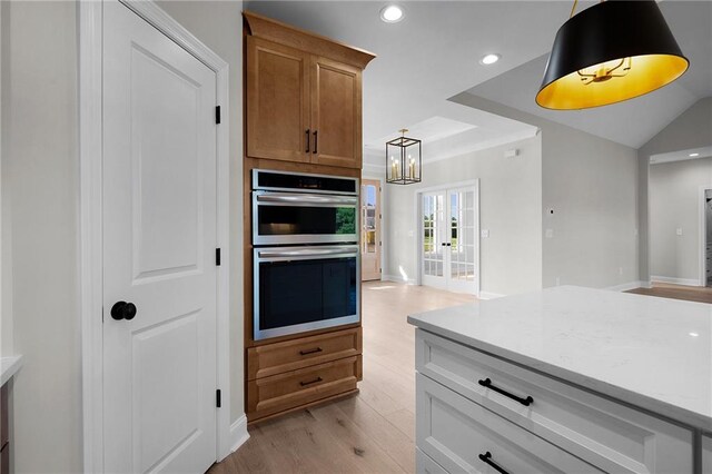 kitchen with double oven, light hardwood / wood-style flooring, white cabinets, a chandelier, and hanging light fixtures