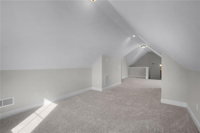 additional living space featuring light carpet and vaulted ceiling