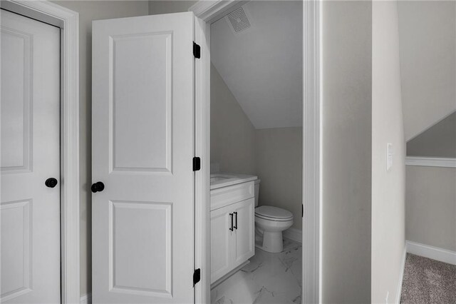 bathroom featuring toilet, vanity, and vaulted ceiling