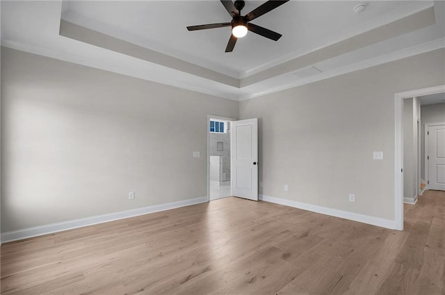 empty room with ceiling fan, light hardwood / wood-style floors, ornamental molding, and a tray ceiling