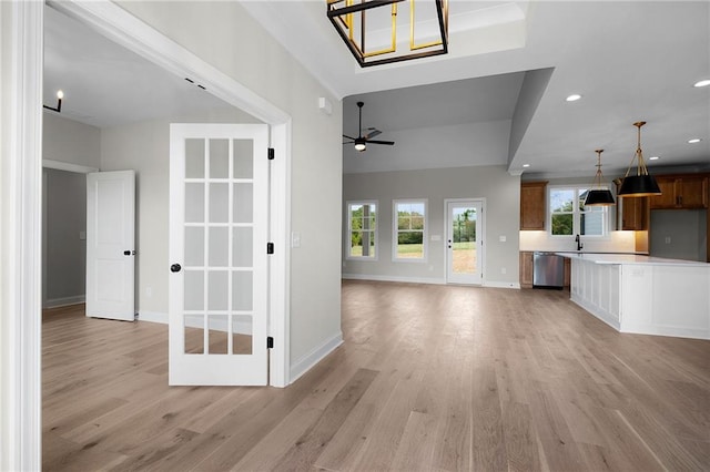 unfurnished living room with ceiling fan, sink, lofted ceiling, and light wood-type flooring