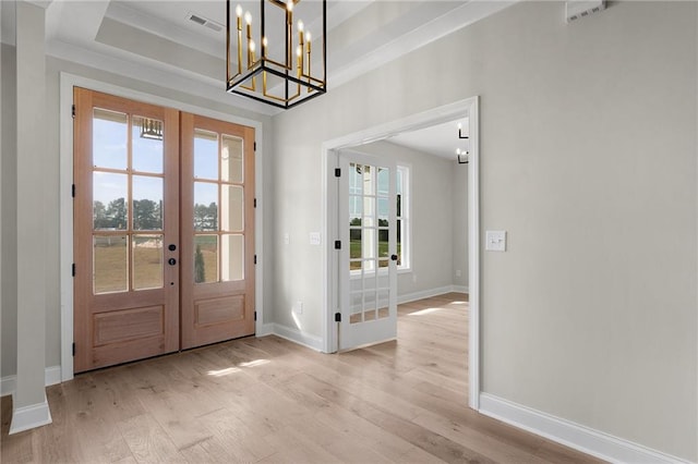 entryway featuring french doors, an inviting chandelier, light hardwood / wood-style flooring, and a raised ceiling