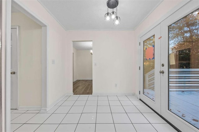 unfurnished room with french doors, light tile patterned flooring, a chandelier, and ornamental molding