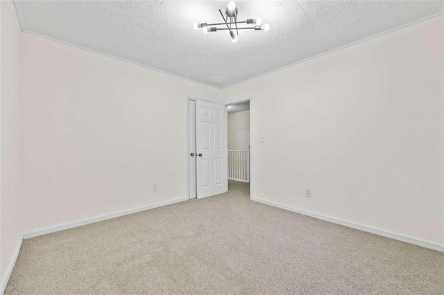 carpeted empty room with a chandelier, a textured ceiling, and crown molding