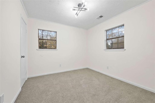 carpeted empty room with ornamental molding, a textured ceiling, and an inviting chandelier