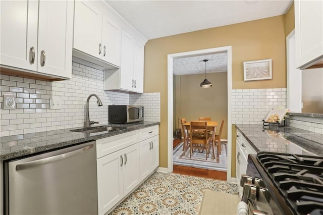 kitchen with a sink, dark stone counters, white cabinetry, and stainless steel appliances