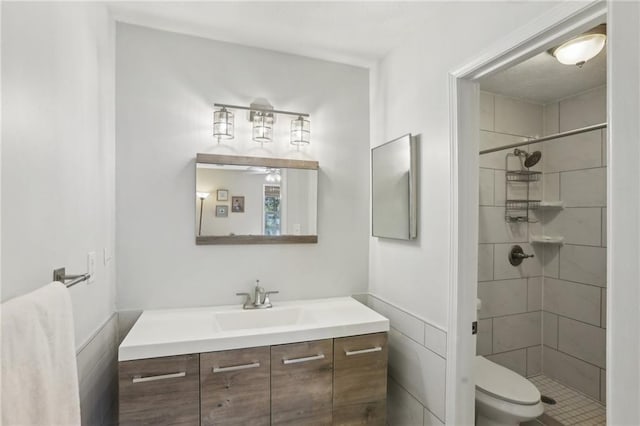 bathroom with tiled shower, toilet, and vanity