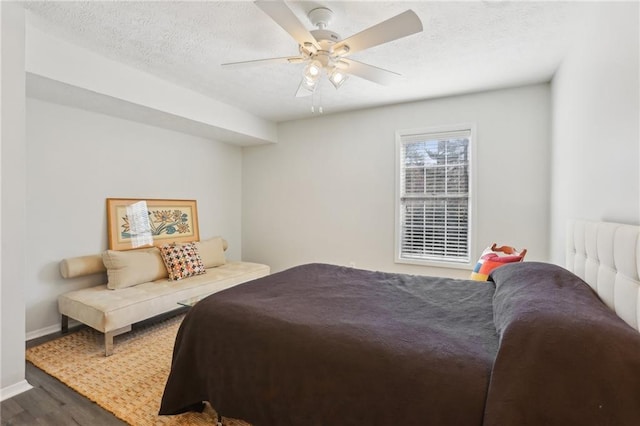 bedroom featuring ceiling fan, a textured ceiling, baseboards, and wood finished floors