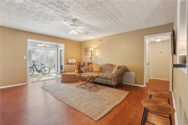 living area with a ceiling fan, baseboards, visible vents, and a textured ceiling