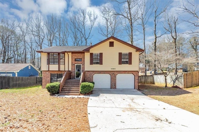 split foyer home with brick siding, fence, concrete driveway, stairs, and an attached garage