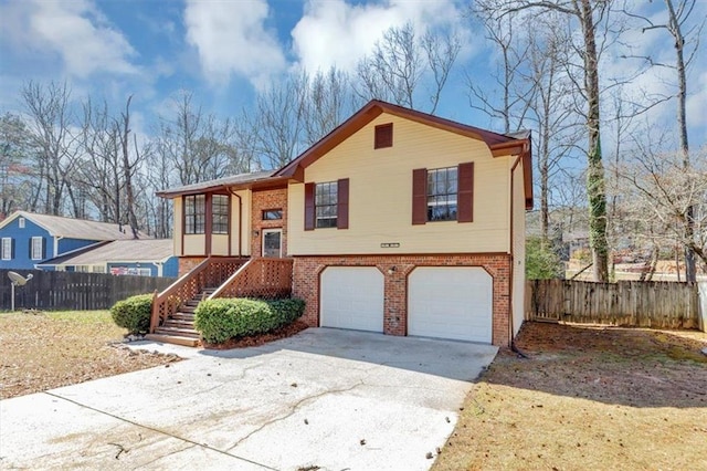 split foyer home with brick siding, concrete driveway, and fence