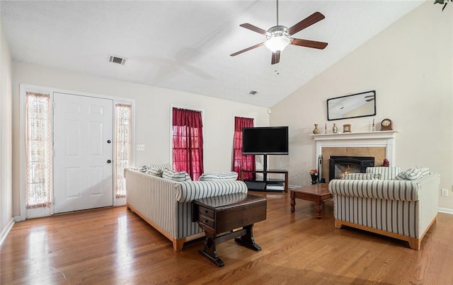 living room with ceiling fan, a fireplace, lofted ceiling, and hardwood / wood-style flooring