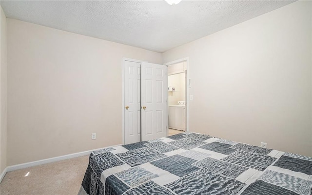 carpeted bedroom with a textured ceiling and washer / clothes dryer