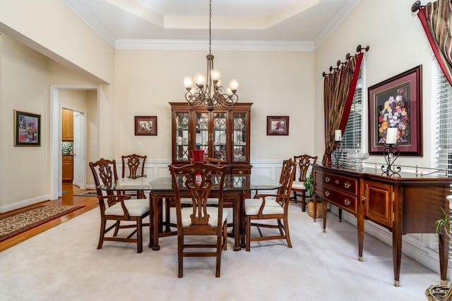 dining room featuring crown molding, light colored carpet, a tray ceiling, and an inviting chandelier