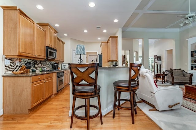 kitchen with ceiling fan, dark stone counters, a kitchen breakfast bar, light hardwood / wood-style flooring, and stainless steel appliances