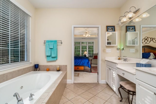 bathroom with ceiling fan, vanity with extensive cabinet space, tiled bath, dual sinks, and tile flooring