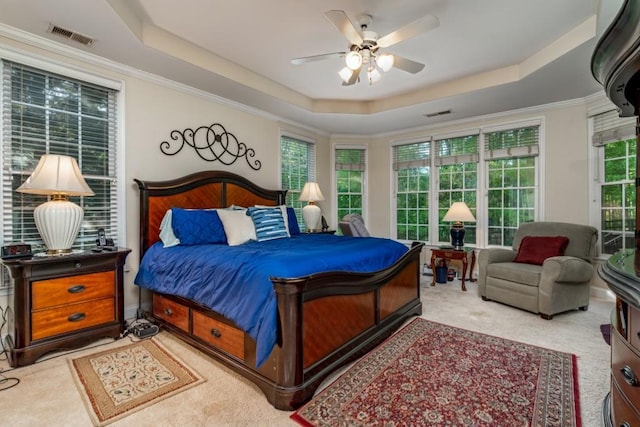 carpeted bedroom featuring ceiling fan, crown molding, and a tray ceiling