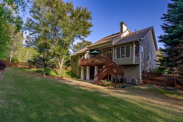 rear view of house featuring central AC unit, a wooden deck, and a lawn