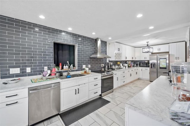 kitchen featuring tasteful backsplash, stainless steel appliances, wall chimney range hood, and a sink