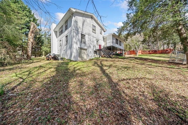 rear view of house featuring a lawn and fence