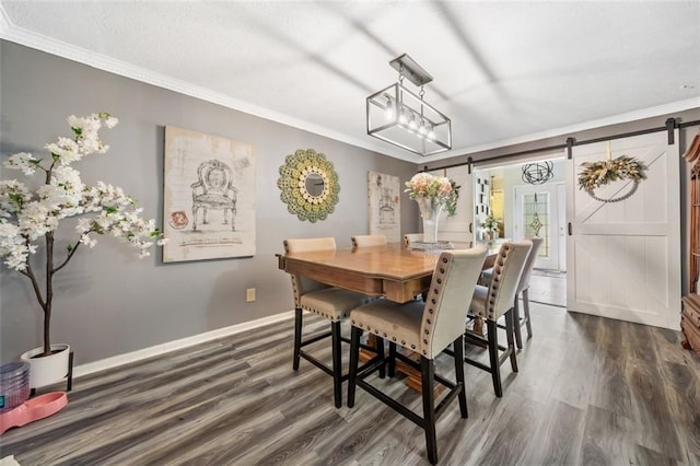 dining area featuring a barn door, dark wood-style floors, baseboards, and ornamental molding