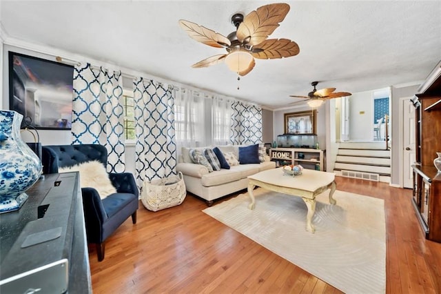 living area featuring hardwood / wood-style floors, stairway, and a ceiling fan