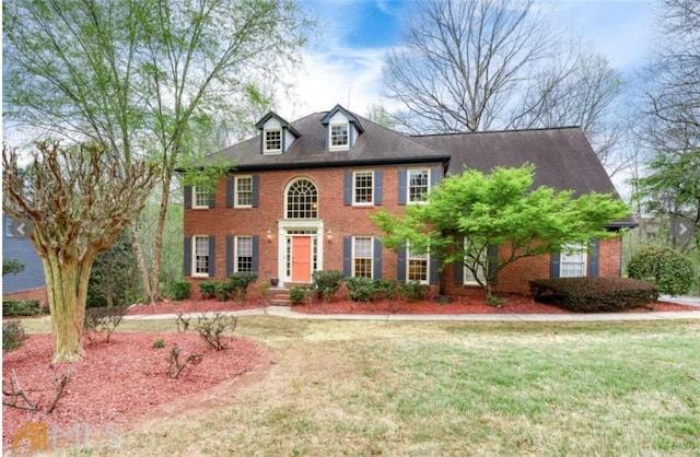 view of front facade with brick siding and a front yard