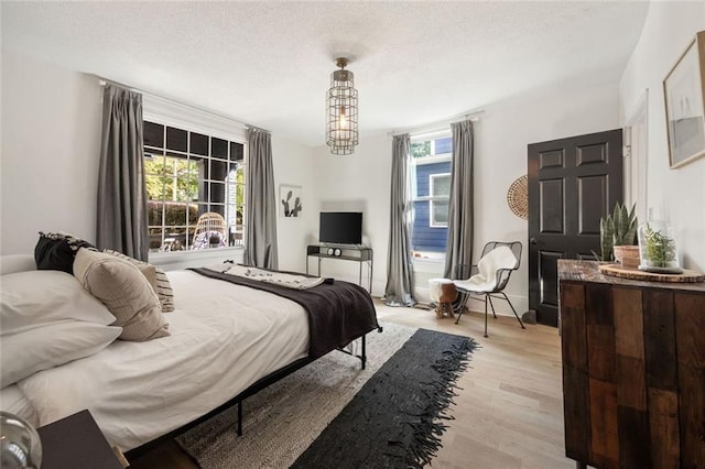 66 Howell St NE, Atlanta, GA 30312 - bedroom featuring multiple windows, light wood-style flooring, a chandelier, and a textured ceiling