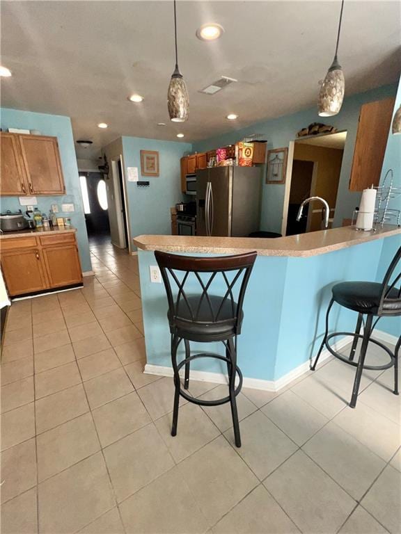 kitchen with pendant lighting, a breakfast bar area, kitchen peninsula, and appliances with stainless steel finishes