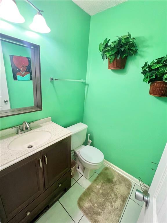 bathroom featuring tile patterned flooring, vanity, a textured ceiling, and toilet