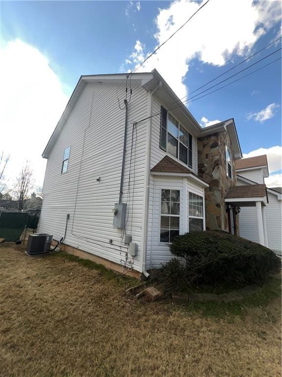 view of side of home with central AC unit and a yard