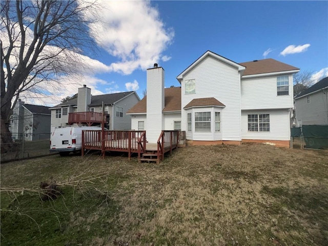 rear view of house featuring a wooden deck and a lawn