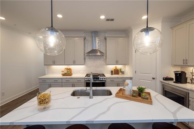 kitchen featuring light stone countertops, appliances with stainless steel finishes, hanging light fixtures, a large island, and wall chimney exhaust hood