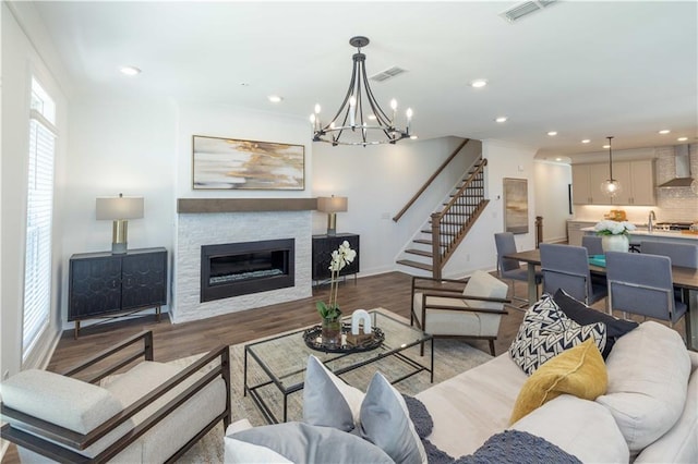 living area with visible vents, stairway, a chandelier, a glass covered fireplace, and recessed lighting