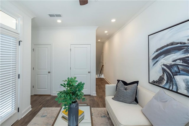 living area featuring crown molding, baseboards, wood finished floors, and visible vents