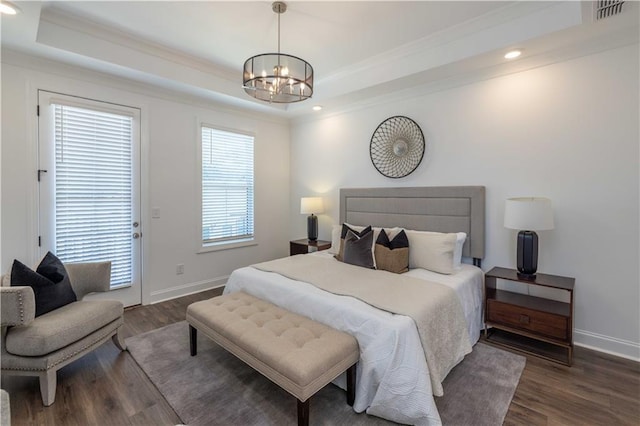 bedroom with crown molding, dark hardwood / wood-style floors, an inviting chandelier, and a raised ceiling