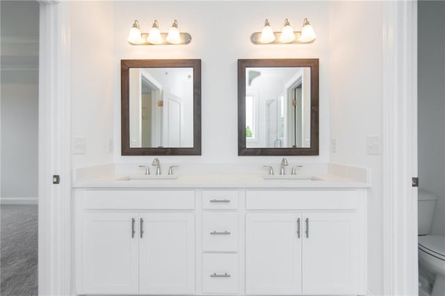 full bath featuring a sink, baseboards, toilet, and double vanity