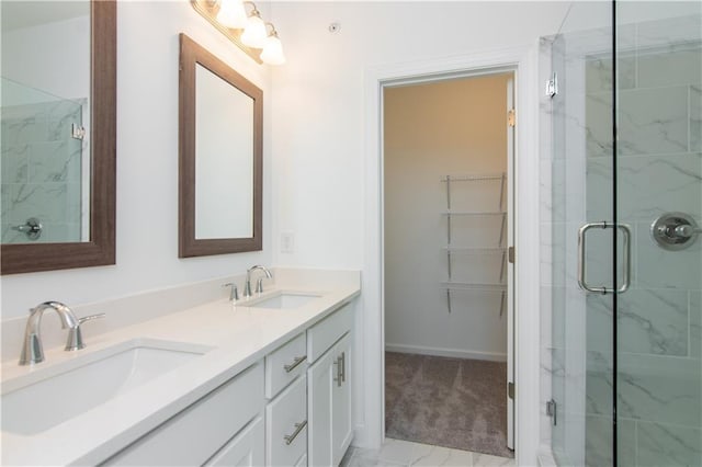bathroom featuring double vanity, a spacious closet, a sink, and a stall shower