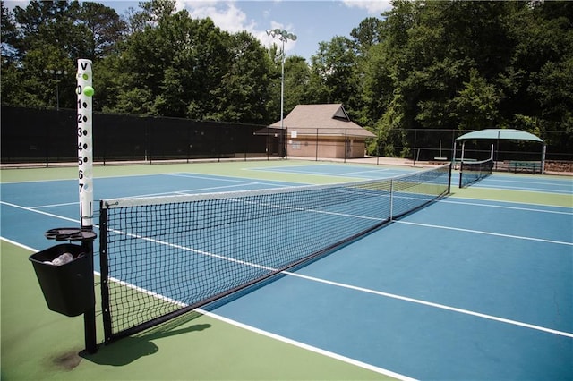 view of tennis court with community basketball court and fence