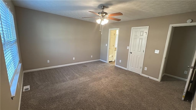 unfurnished bedroom with a textured ceiling, ceiling fan, and dark carpet