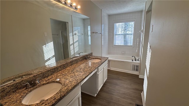 bathroom with hardwood / wood-style flooring, a washtub, and vanity