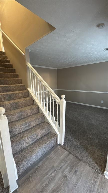 staircase with a textured ceiling and wood-type flooring