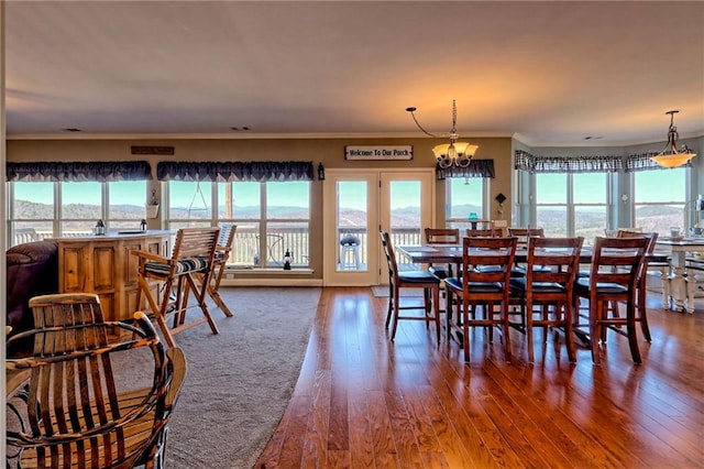 dining space with a wealth of natural light, a chandelier, crown molding, and wood finished floors