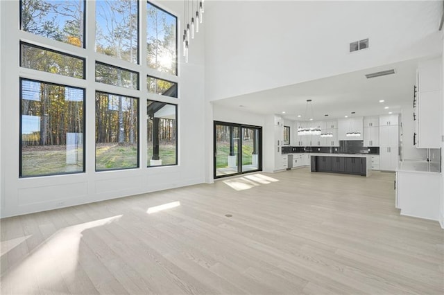 unfurnished living room featuring a high ceiling and light wood-type flooring