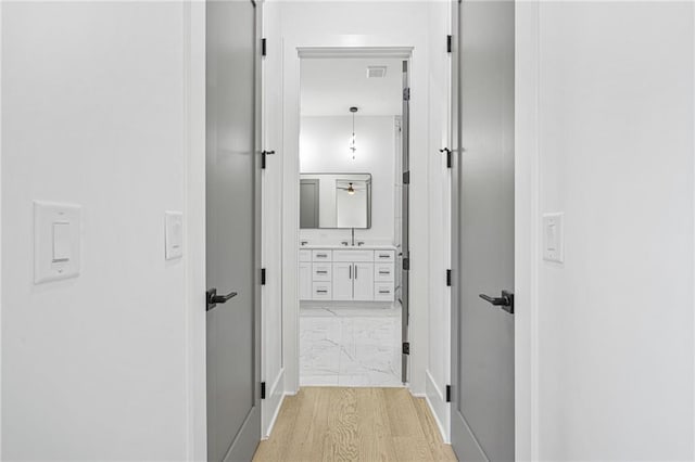 hallway with sink and light hardwood / wood-style floors