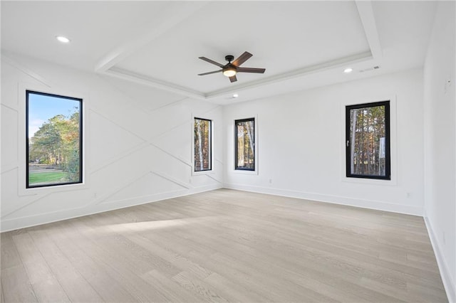 empty room featuring a raised ceiling, ceiling fan, and light hardwood / wood-style flooring