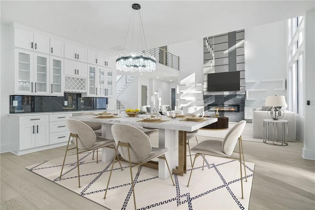 kitchen featuring a fireplace, light hardwood / wood-style floors, pendant lighting, decorative backsplash, and white cabinetry